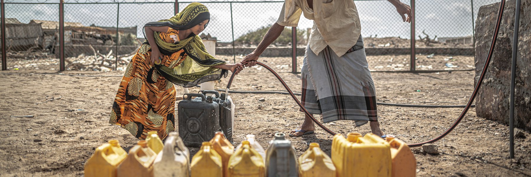 Naaser Mohamed Fakih and his granddaughter fill water containers with water