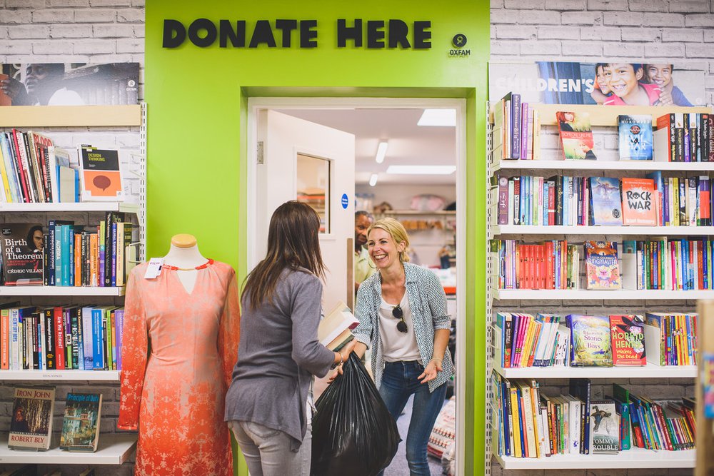A lady donating books and a blackbag of clothes to the Cowley Road Shop, Oxford.