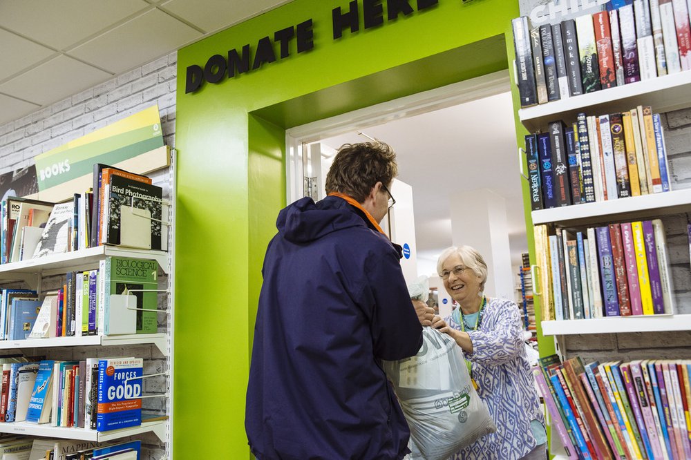 A man donates a bag of goods to his local Oxfam shop