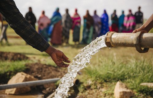 Fresh clean water shoots from a pipe into a hand.