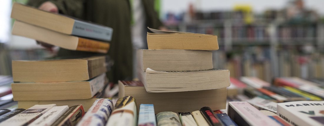 Someone reaches for a stack of books on a display