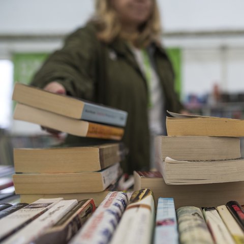 Someone reaches for a stack of books on a display