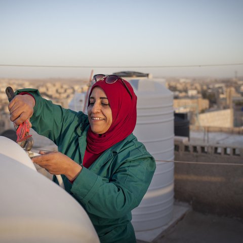 Mariam, a woman aged 44, is fixing the water tank on the rooftop of her house in the town of Zarqa in Jordan.