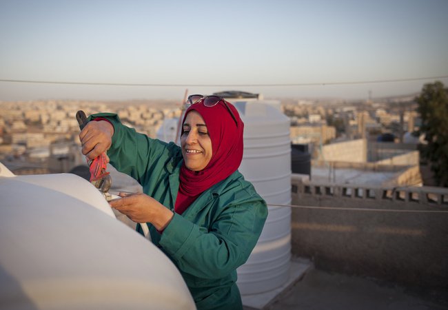 Mariam, a woman aged 44, is fixing the water tank on the rooftop of her house in the town of Zarqa in Jordan.