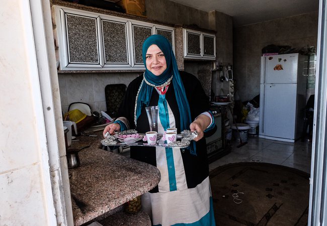 Huda carrying a tea tray at home in Jordan