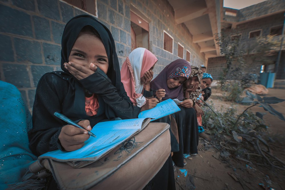 A group of young girls sit studying outside a school in Yemen.