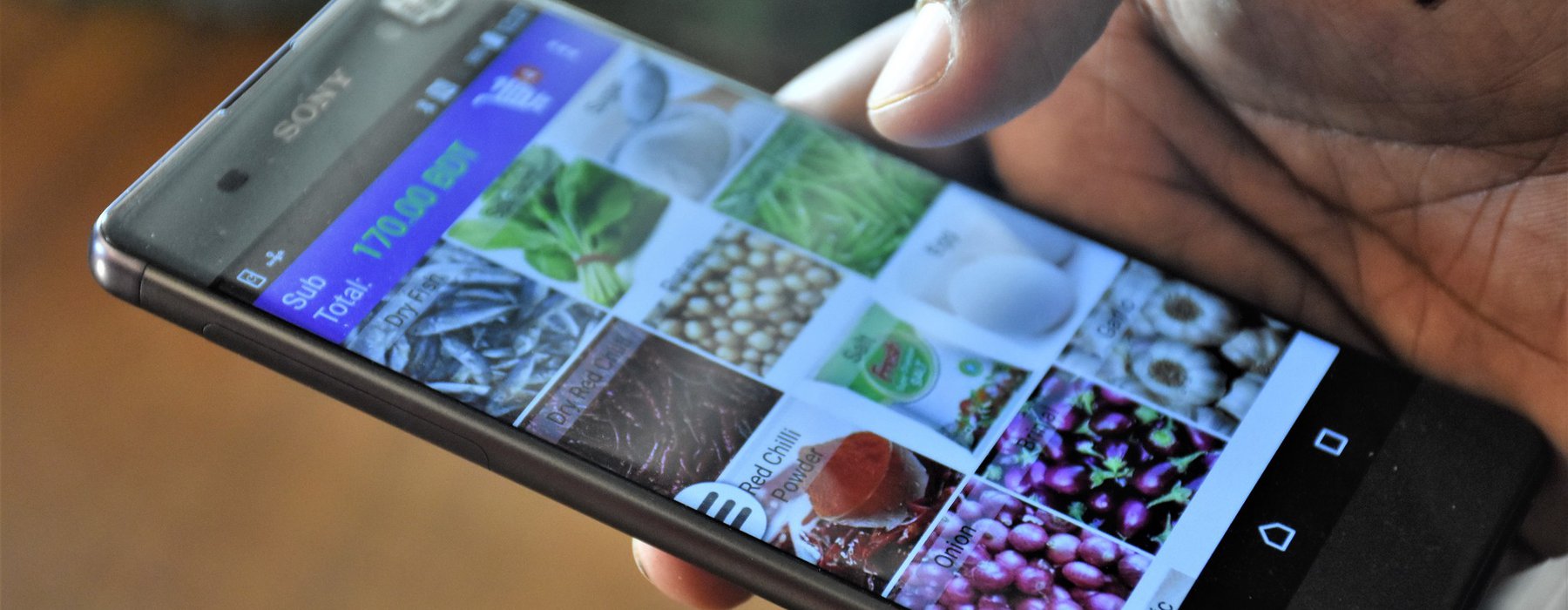 A picture of a mobile phone in a hand with photos of vegetables on the screen