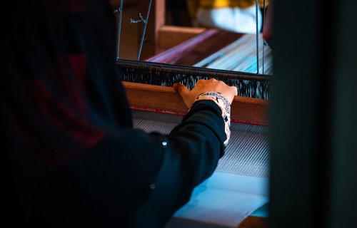 A woman's hand is on a weaving machine