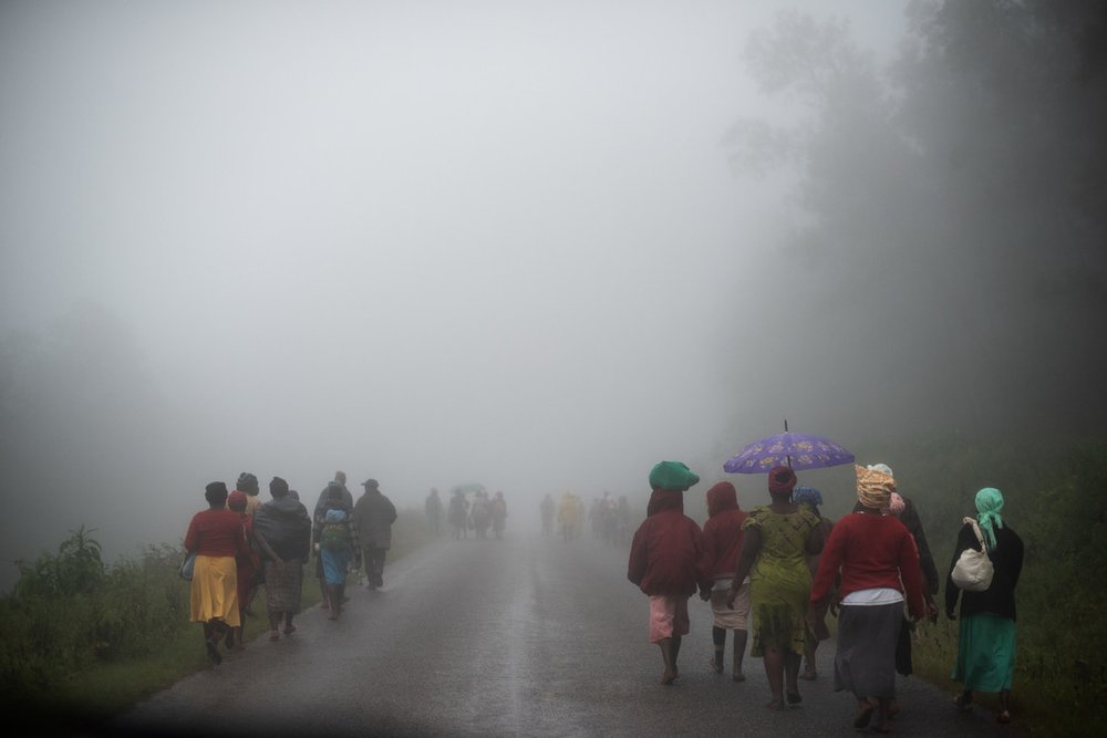 People walk along a road in the rain towards a food distribution point in Zimbabwe after Cyclone Idai caused heavy rains, flooding and landslides in 2019.