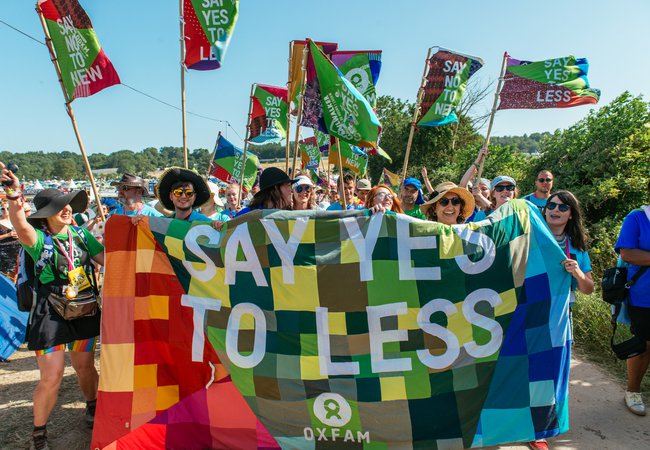 A group of volunteers stand by a patchwork banner that says 'say yes to less'