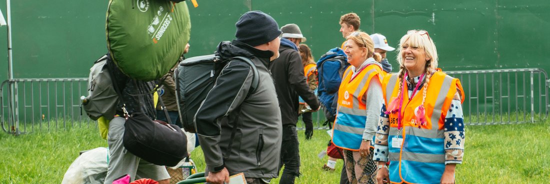 Oxfam stewards greeting people with camping gear