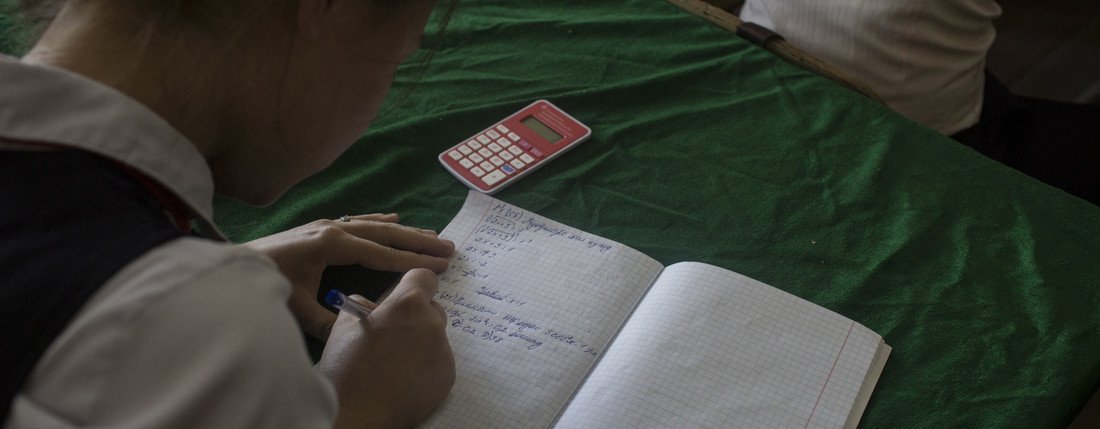 A school girl in Tajikistan is doing some algebra in her class.