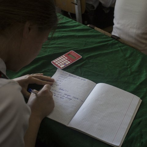 A school girl in Tajikistan is doing some algebra in her class.