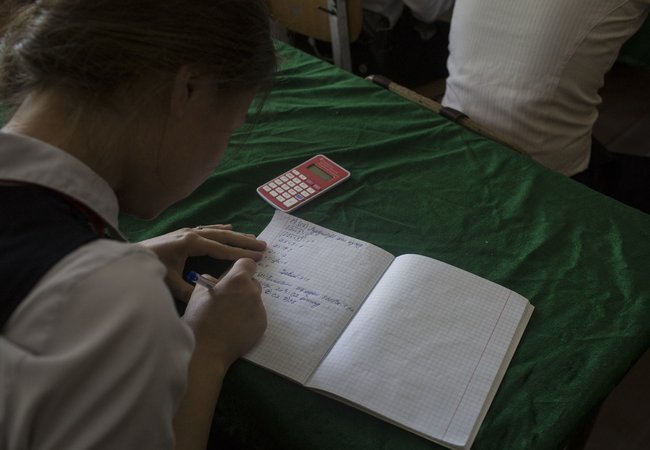 A school girl in Tajikistan is doing some algebra in her class.