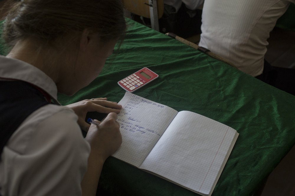 A school girl in Tajikistan is doing some algebra in her class.