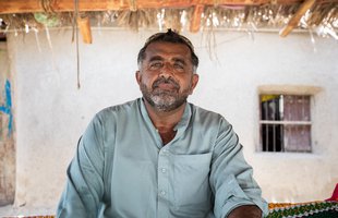 A portrait of Muhammad Siddique sitting outside a building