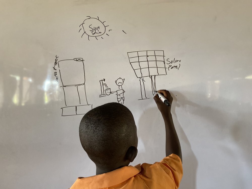 Child drawing on a whiteboard in a classroom in a school in Ghana