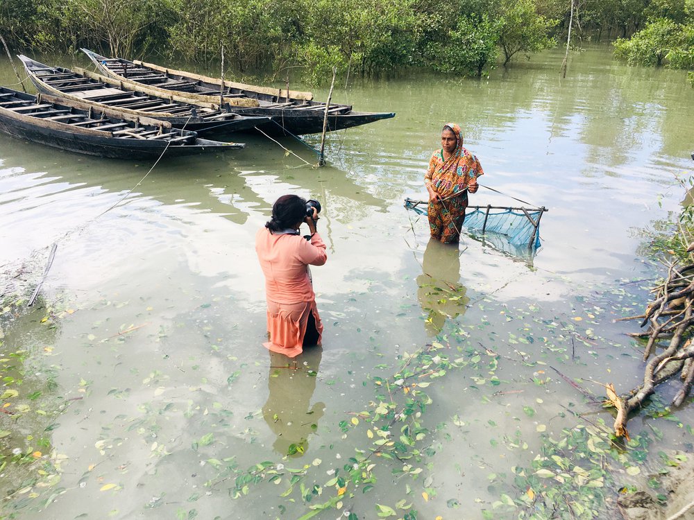 Fabeha Monir photographs a woman by a fishing net in floodwater in Bangladesh