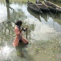 Fabeha Monir wades through floodwater in Bangladesh holding a camera