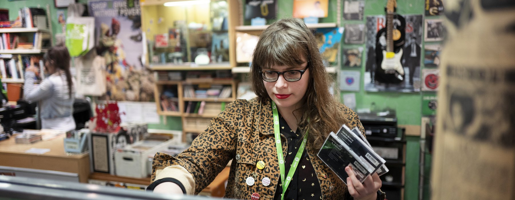 Music shop volunteer, Lucy, arranges CD display in Oxfam music shop, Byres Road, Glasgow