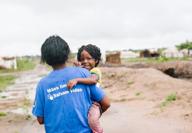 Sonia carries her child over the mud