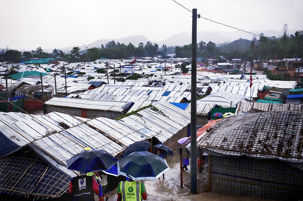 Oxfam staff walk down a path through the middle of the refugee camp