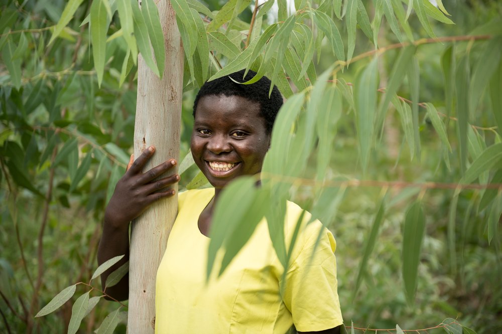Jessy Nkhoma holds a tree she planted when she was younger at in her village in Kasungu District on Monday, March 22, 2021