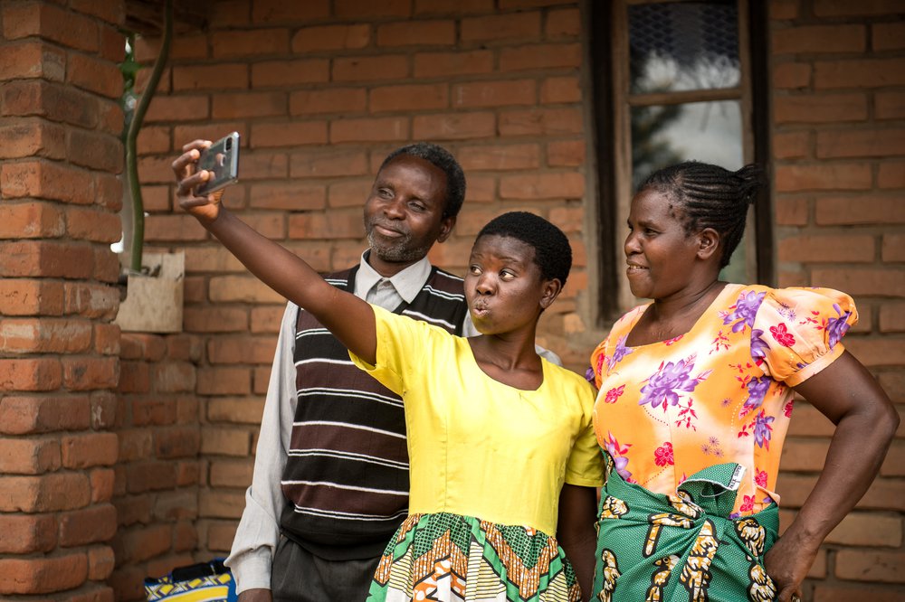 Jessy has fun pouting at a phone camera as her parents stand either side of her smiling