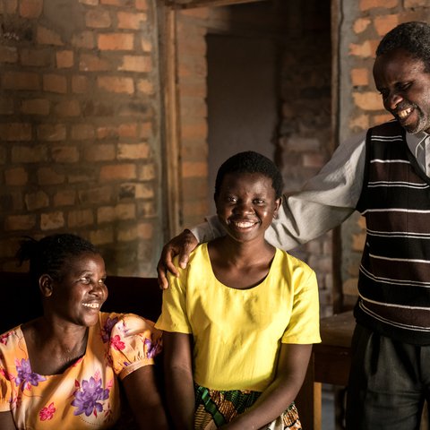 Jessy and her parents smiling in a family portrait.