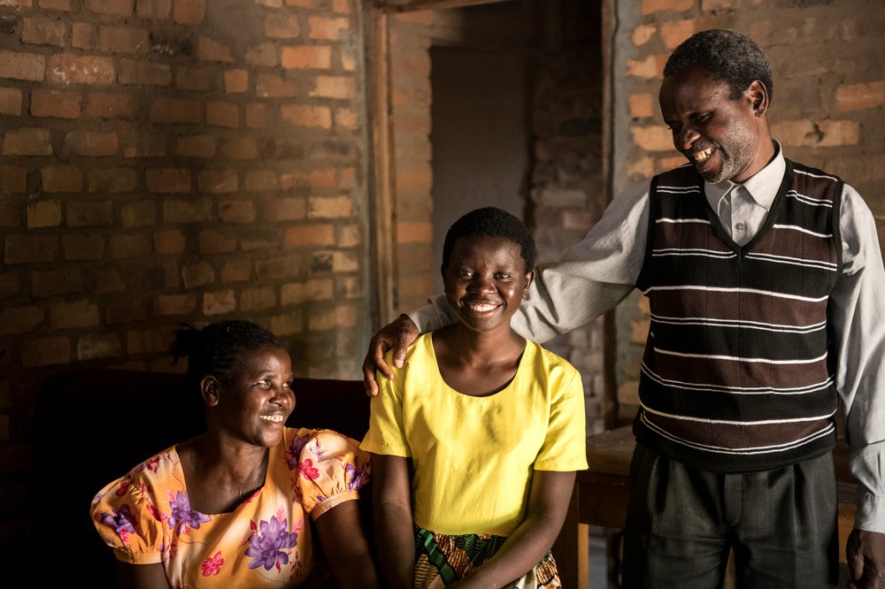 Jessy and her parents smiling in a family portrait.