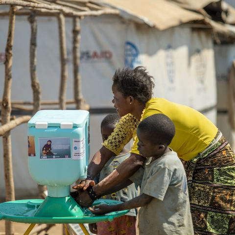 Lumbumba shows her young children how to use new hand washing kit, Democratic Republic of Congo