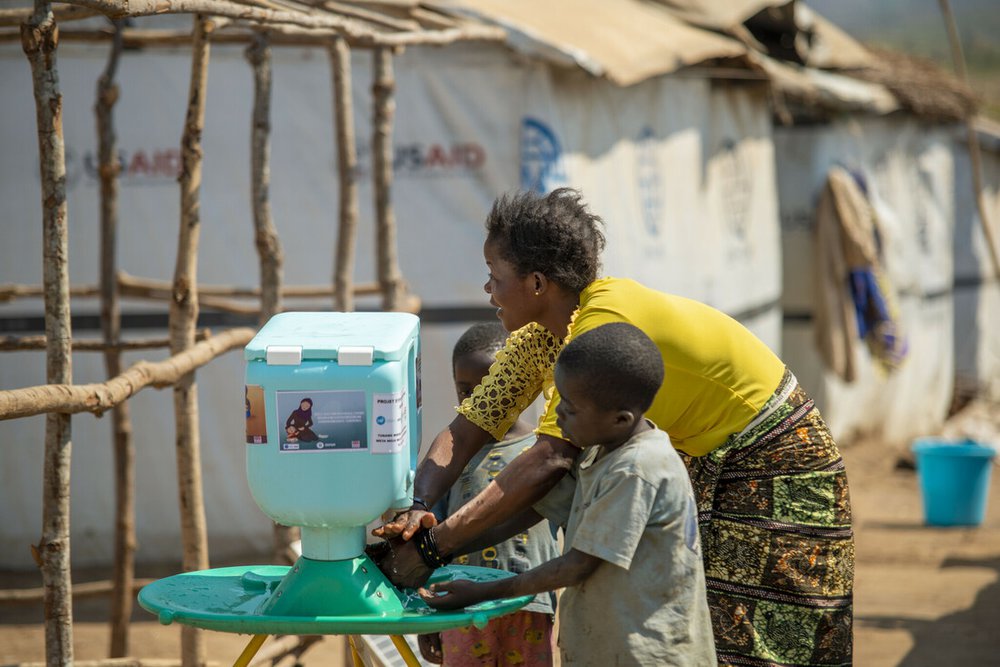 Lumbumba shows her young children how to use new hand washing kit, Democratic Republic of Congo