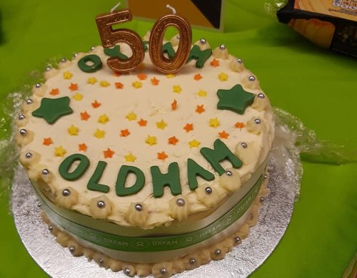 A white cake with green letters that say '50 Oldham'