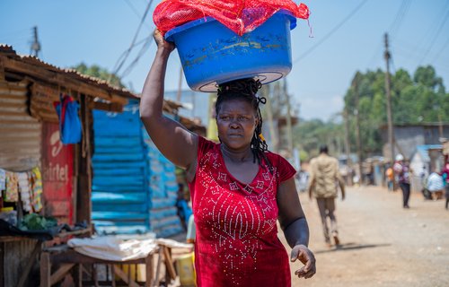 Joyce Nyarangi Oyogi carries a basin on her head with dirty laundry in Kibarage, Nairobi, Kenya.