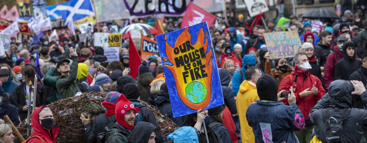 Climate activists marching in Glasgow during COP26 holding an array of banners and placards.