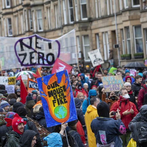 Climate activists marching in Glasgow during COP26 holding an array of banners and placards.