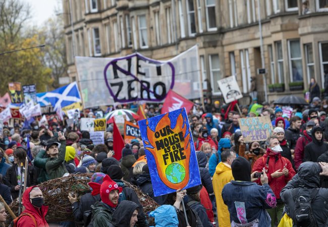 Climate activists marching in Glasgow during COP26 holding an array of banners and placards.