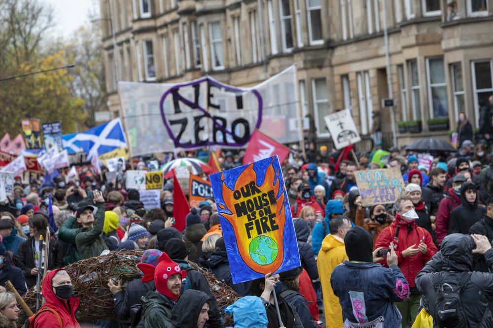 Climate activists marching in Glasgow during COP26 holding an array of banners and placards.