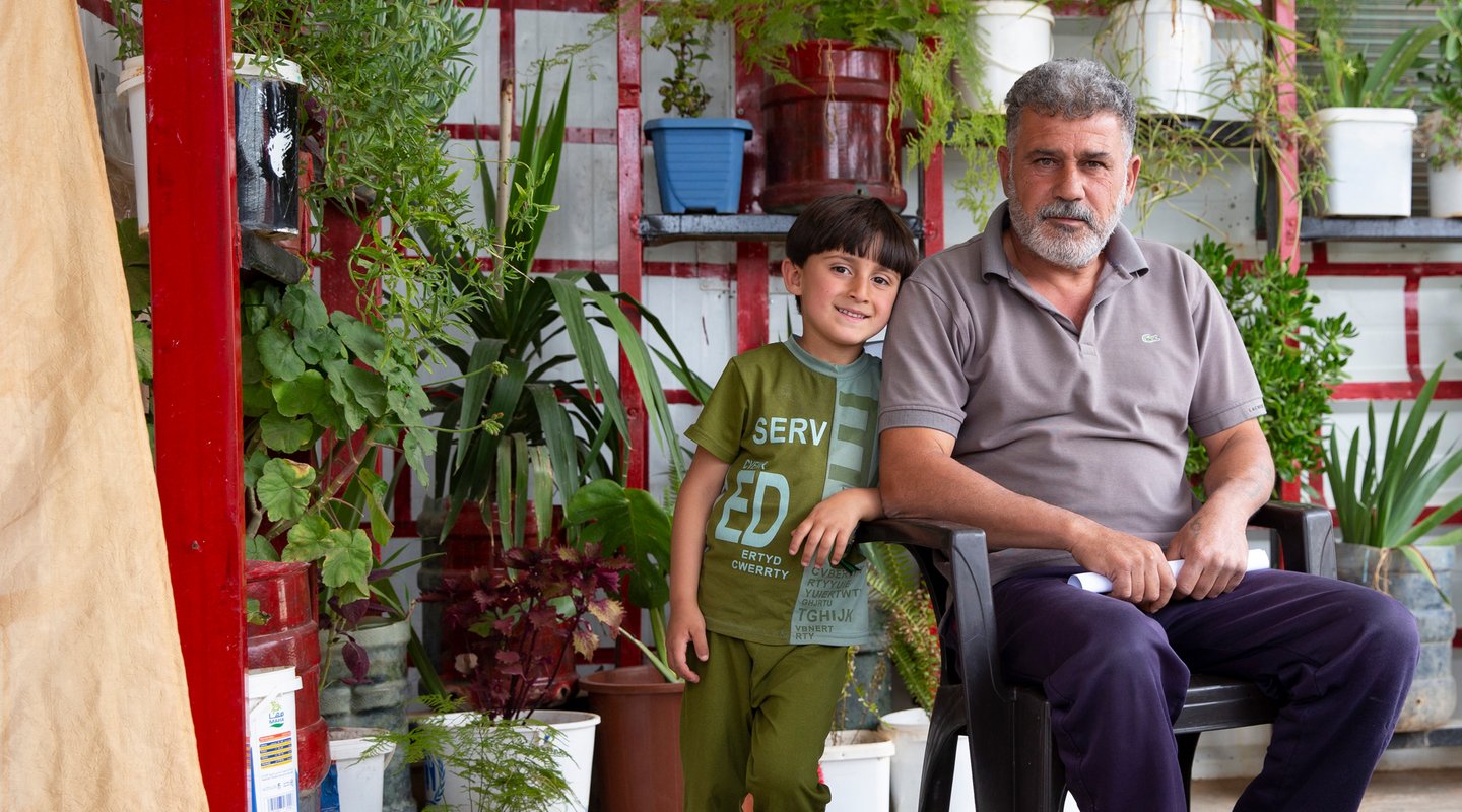 Abu and his son with their pot plants in their front yard