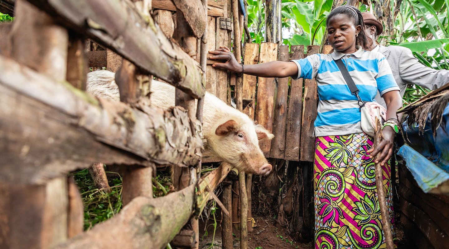 Marie Nsimire, a businesswoman in DRC stands with her pigs