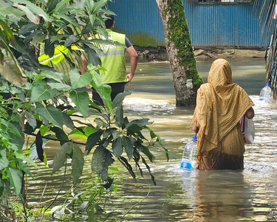 A woman receives essential supplies of clean water, ORS, and dry food provided by Oxfam in the aftermath of the 2024 Bangladesh floods.