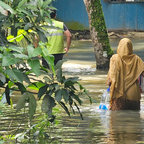 A woman receives essential supplies of clean water, ORS, and dry food provided by Oxfam in the aftermath of the 2024 Bangladesh floods.