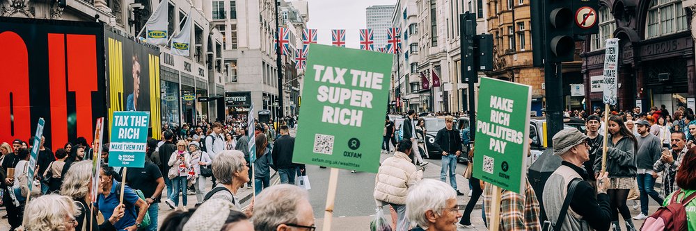Protesters march through central London holding placards reading 'Tax the rich' and 'Make rich polluters pay'