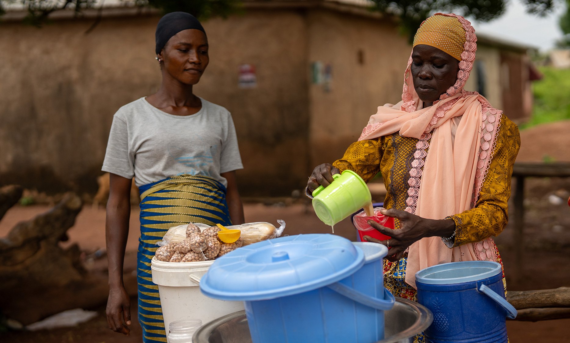 Two women preparing food at a small roadside stall, running their business together.