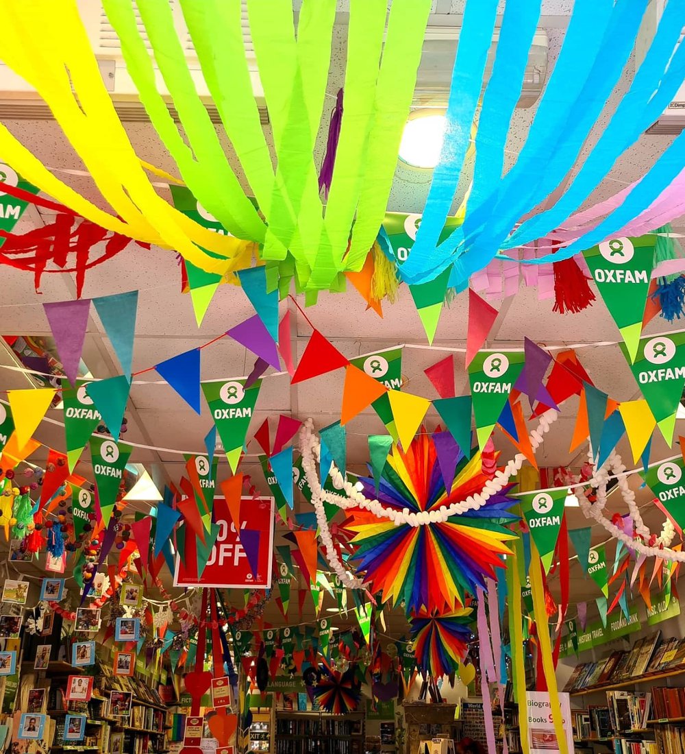 Inside the Oxfam Brighton shop during Pride month with loads of rainbow streamers and bunting