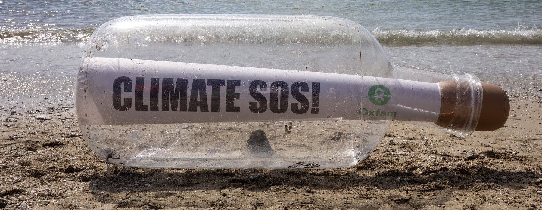 A giant message in a bottle reading Climate SOS has washed up on the beach