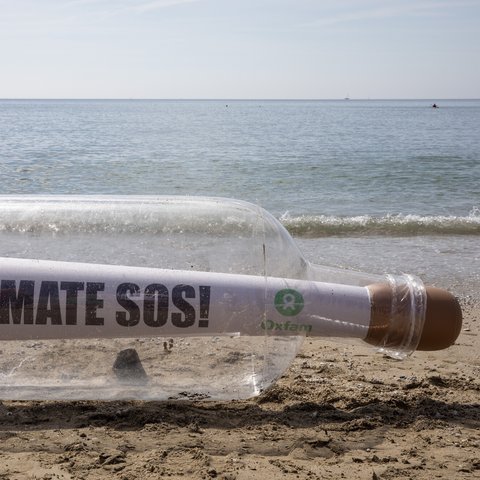 A giant message in a bottle reading Climate SOS has washed up on the beach