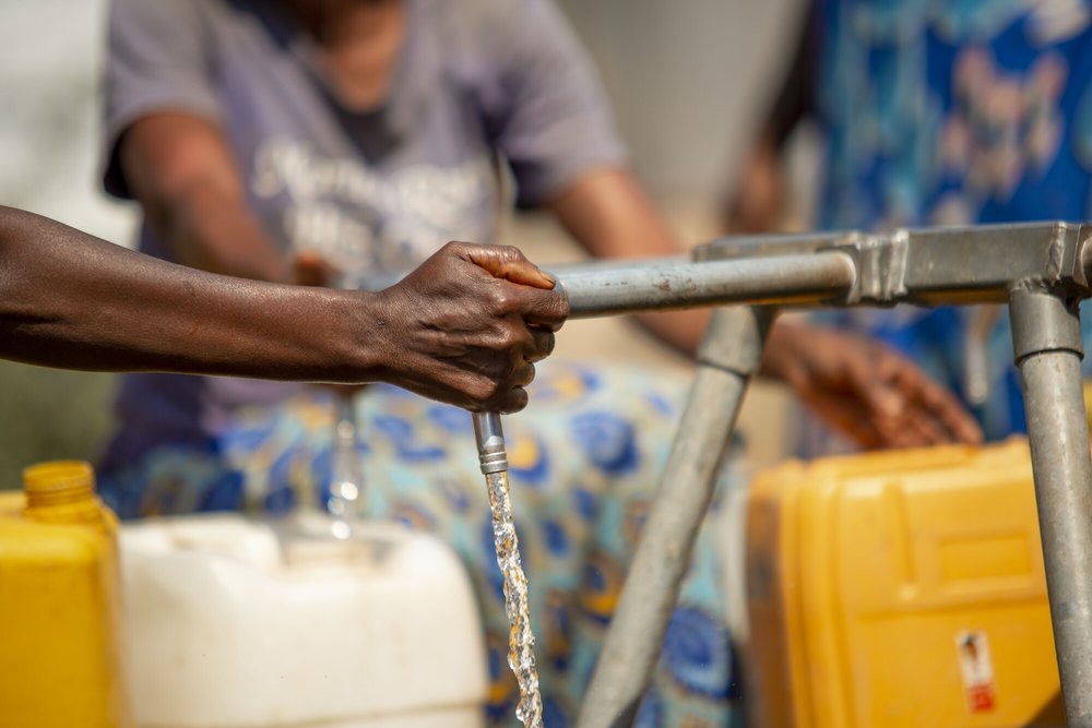 Close up of water being collected from a tap in the Democratic Republic of Congo in a yellow container.