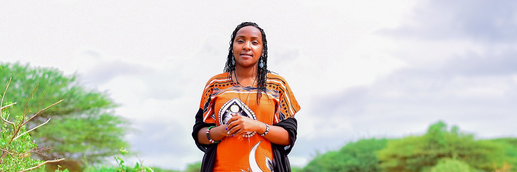 Elizabeth Wathuti standing in a dry landscape in Wajir, Kenya