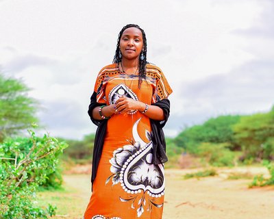Elizabeth Wathuti standing in a dry landscape in Wajir, Kenya
